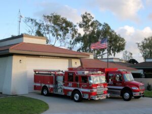 Fire station 5 has terracotta roof tiles and it's large garage door open with engine 65 parked in the driveway on a sunny day.