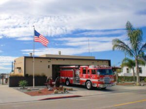 Fire station number 3 with engine 63 parked in the driveway and the American flag behind it.